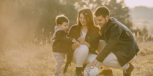 A cheerful family bonding outdoors with a soccer ball, enjoying a sunny day in the grass.