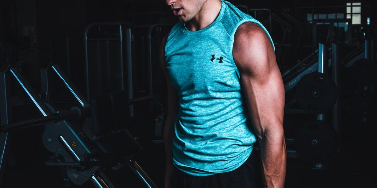 Man exercising indoors, lifting dumbbells for strength training in a Towson gym.