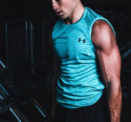 Man exercising indoors, lifting dumbbells for strength training in a Towson gym.